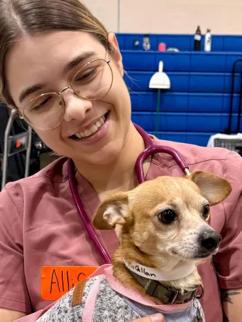 A woman holding a small dog
