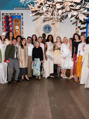 A large group of people pose together in an elegant, art-filled room.