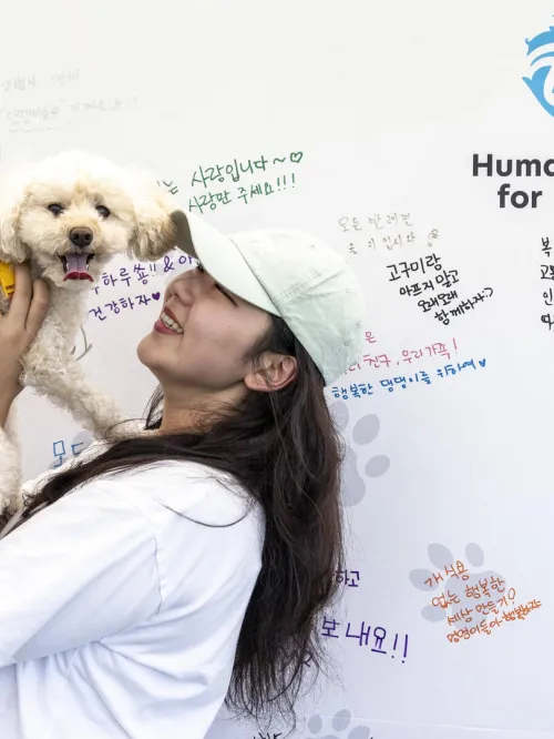 Woman holding a dog in front of a board with handwritten notes.