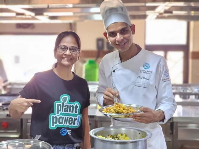 A woman wearing a "Plant Power!" T-shirt poses with a Humane World for Animals chef at a chef training event.
