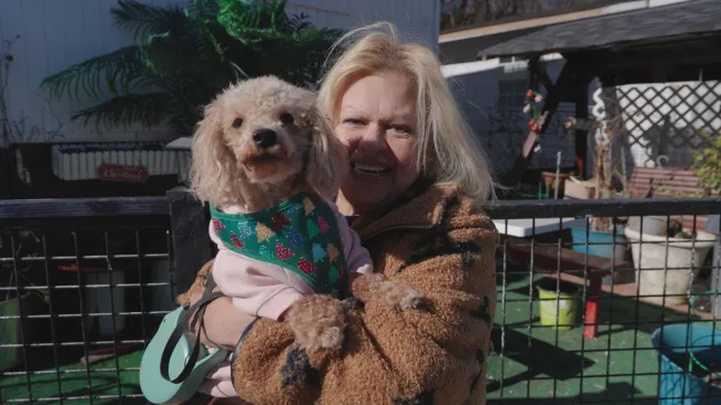 woman smiling, holding a dog in her arms