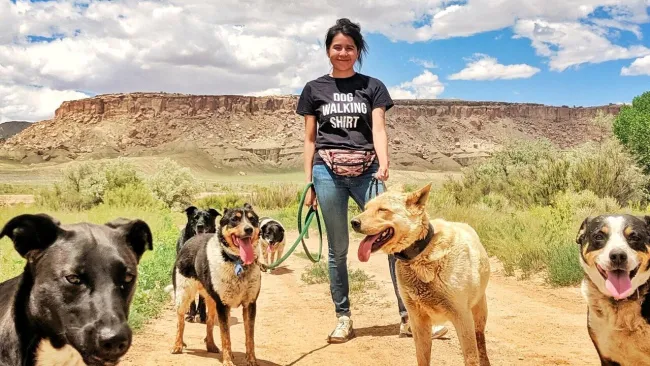 woman stands in the desert with group of dogs