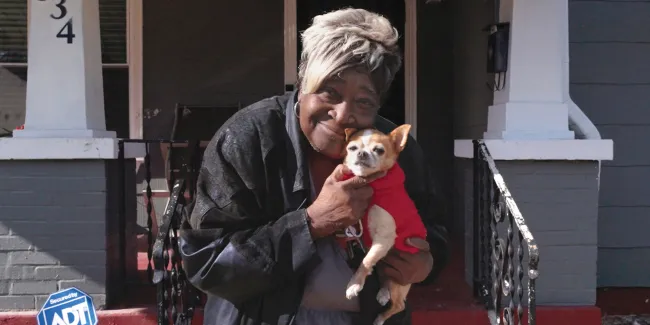 A woman holding a little brown and white dog. 