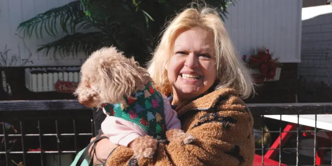 A woman holding a tan dog. 
