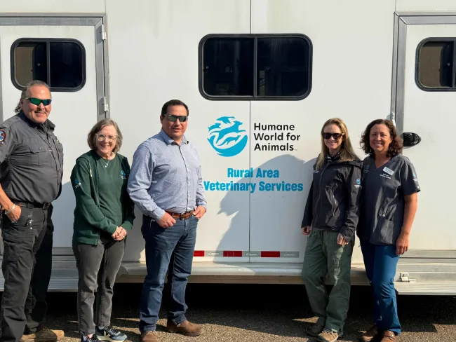 Several people standing in front of mobile veterinary clinic