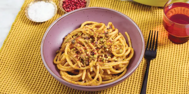 Plate of spaghetti topped with crushed pistachios.