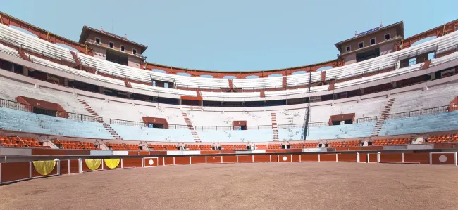 Empty bullfighting arena with tiered seating and a central ring.