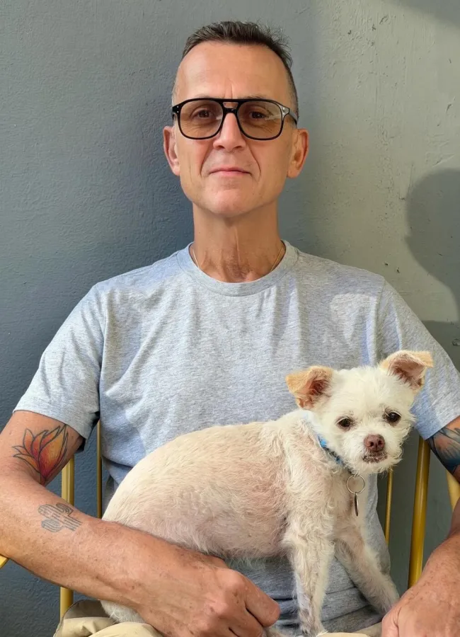 A person holding a small white dog on their lap. 