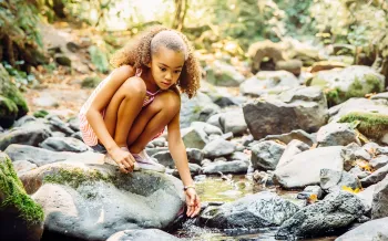 Young girl playing near stream in forest