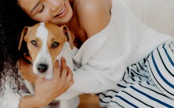 A woman hugs her dog goodbye, but he looks sad and doesn't want her to leave