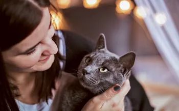 A woman cuddles with her cat who is looking at her adoringly.