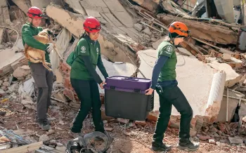 Disaster responders carry a stranded mother dog from the rubble.