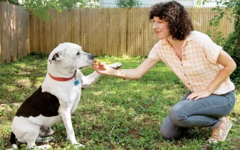 Woman outside with dog, feating him a treat