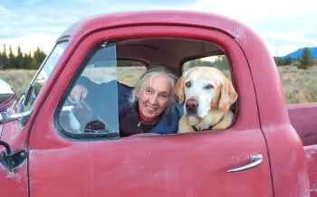 Jane Goodall in a red truck with a dog.