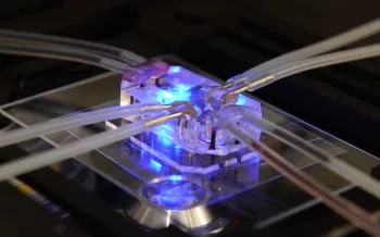 A close-up shows a microfluidic device with clear tubing connected to a transparent block 