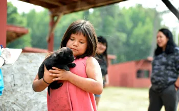 Girl holds a puppy at a Pets for Life event where we provided veterinary care for dozens of families