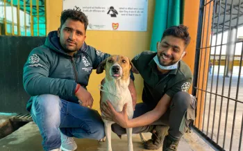 Two people pose with a dog