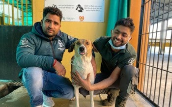 Two people pose with a dog