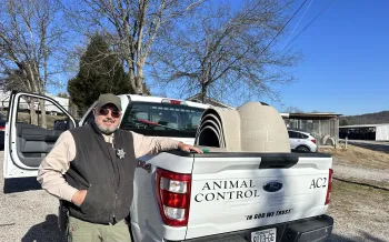 A man stands next to a truck filled with doghouses