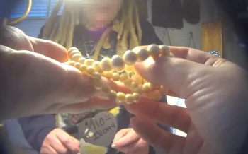 The image shows a person holding a string of ivory beads in their hands. 