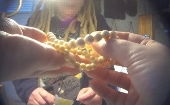 The image shows a person holding a string of ivory beads in their hands.