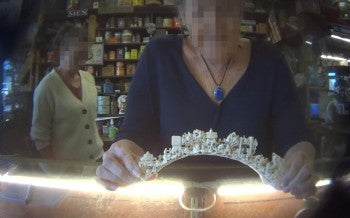 The image shows an intricately carved ivory or bone arch being held by a person.
