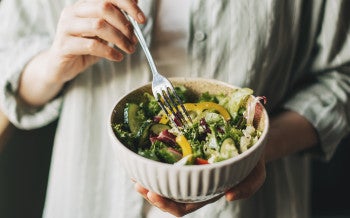 Close up of a person holding a bowl filled with salad