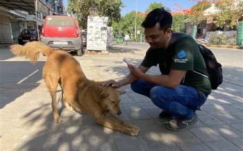 a man sitting on the sidewalk with a dog