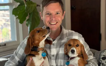 Two beagle puppies rescued from a research laboratory are held by their adoptive father