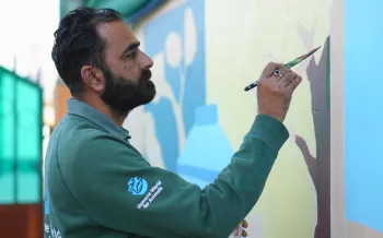 Man painting mural on wall.