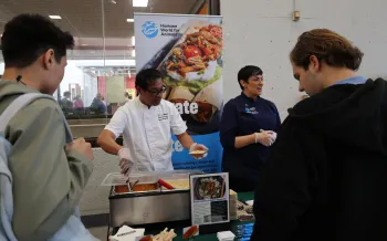 a group of people standing around a table with food on it