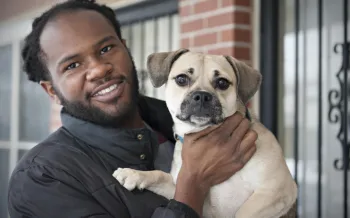 The image shows a person holding a small dog.