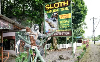 The entrance to a "Sloth Watching Trail," with a large sign advertising the attraction.