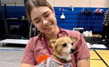 A woman holding a small dog