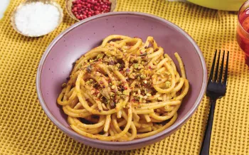 Plate of spaghetti topped with crushed pistachios.