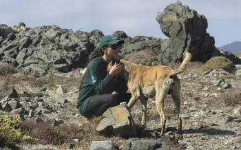 A person crouching down next to a dog.