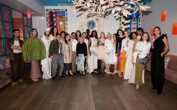 A large group of people pose together in an elegant, art-filled room.
