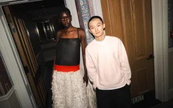 Two people stand side by side in a hallway.